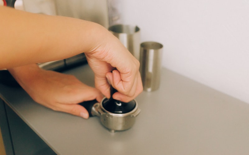 A coffee maker on a kitchen counter next to a bottle of white vinegar and a microfiber cloth, ready for a deep cleaning session