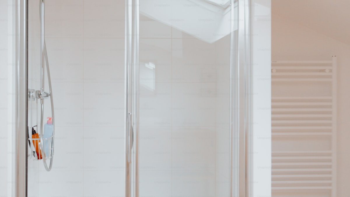 Person using a squeegee on a large glass patio door with a garden visible outside