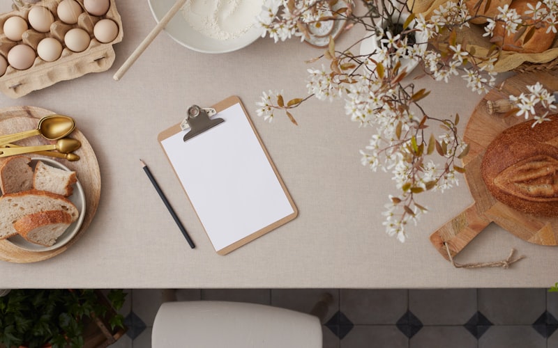 Overhead shot of a kitchen counter with neatly organized groceries, a calculator, and a handwritten meal plan on a notepad