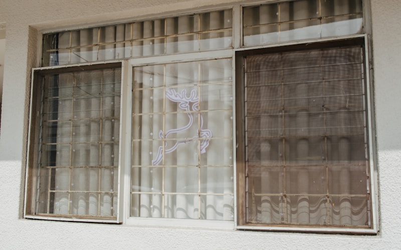 A person holding their hand near a window frame to feel for cold air drafts coming through gaps in the weatherstripping