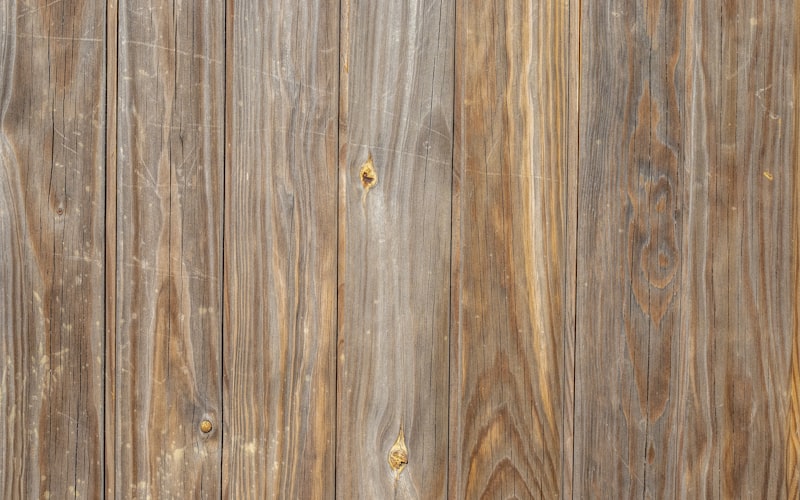 Close-up of a door hinge with a cardboard shim being placed behind the hinge plate on the door frame