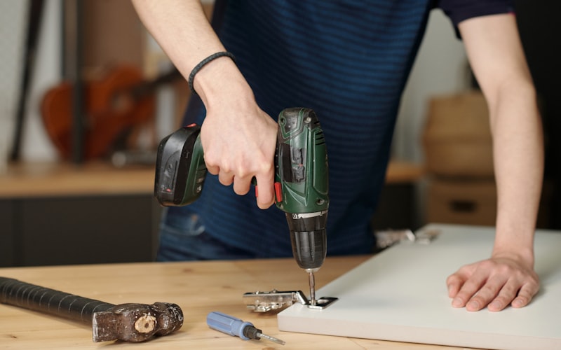 A hand holding a sanding block and sanding the edge of a door propped on sawhorses