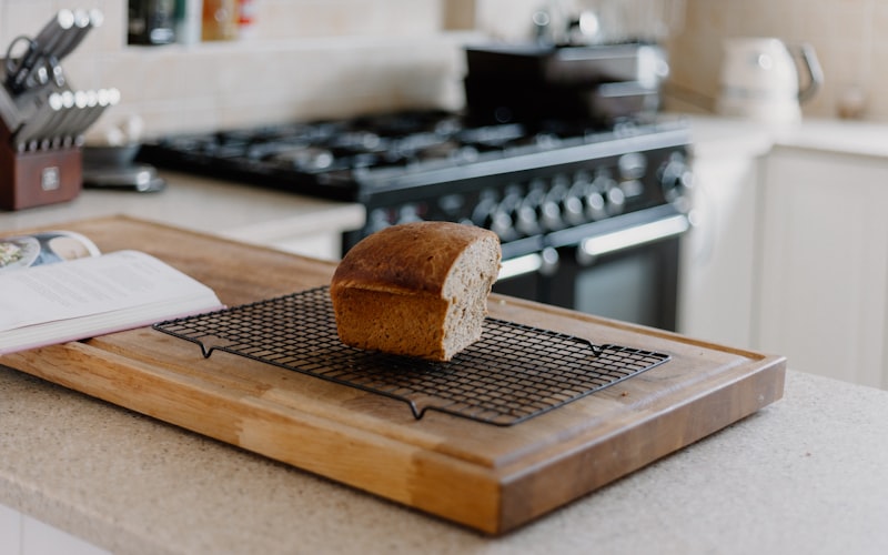 Bread stored in a linen bag next to a wooden bread box on a kitchen counter