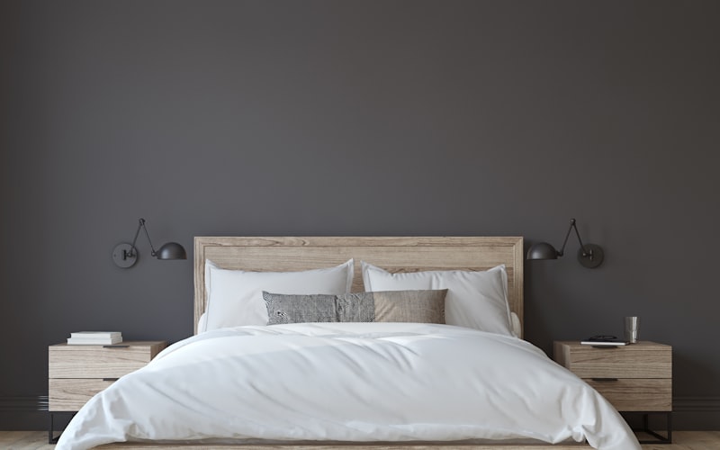 A dark, cool bedroom at night with blackout curtains drawn and a bedside lamp providing soft warm light