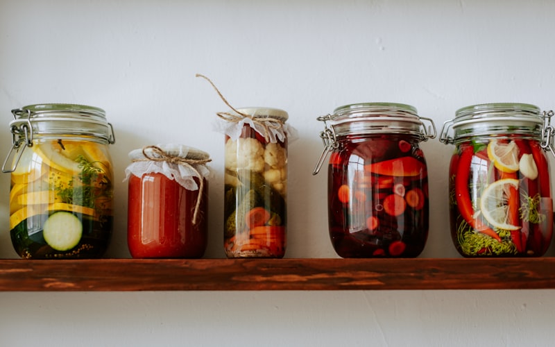 A neatly organized spice drawer with uniform glass jars, clear labels facing up, and an angled wooden insert