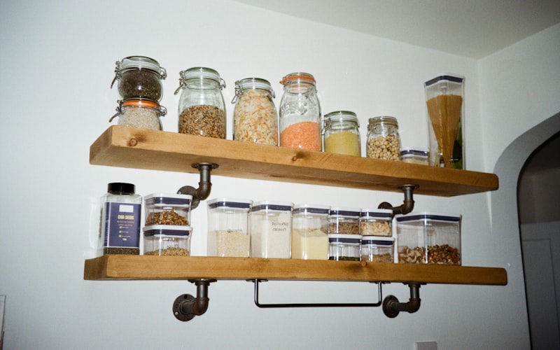 A spice cabinet with a tiered shelf riser showing three visible rows of labeled spice jars inside a standard kitchen cabinet