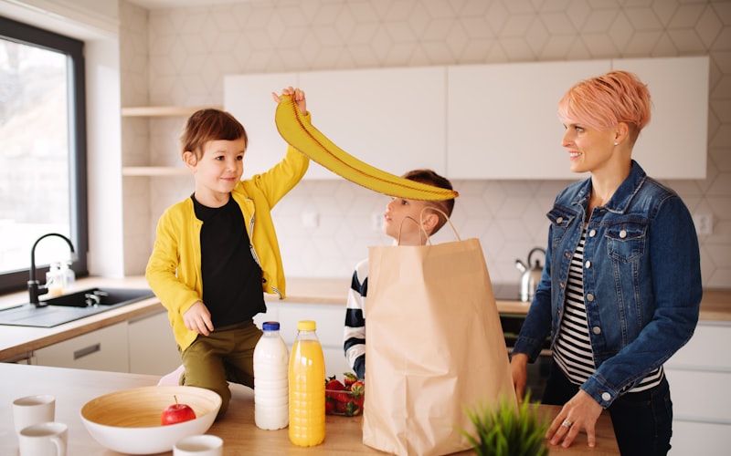 Brown paper bags on a kitchen counter with fruit visible inside, next to ripe bananas