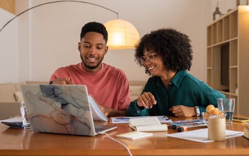 Organized desk with budgeting notebook and laptop showing online shopping